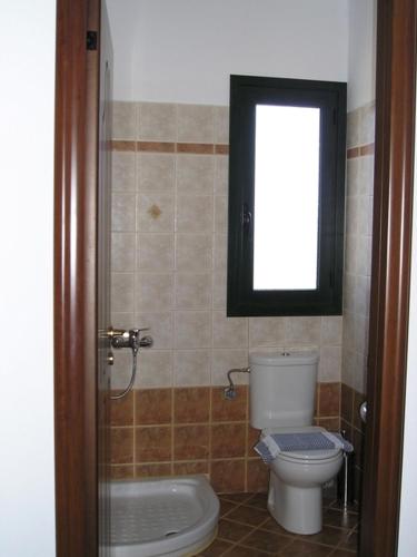a bathroom with a toilet and a window at Golden Beach Inn in Chrysi Ammoudia