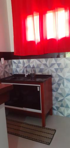 um micro-ondas numa cozinha com uma cortina vermelha em Chalé Bela Vista em Serra Negra