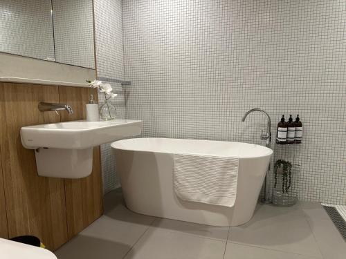 a bathroom with a sink and a bath tub and a sink at Palko - Stylish in the City in Canberra