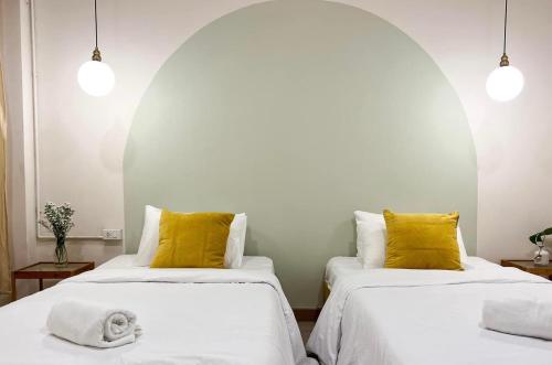 two beds with yellow pillows in a room at La Moon House in Salaya