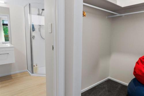 a bathroom with white walls and a shower in a room at Recline on Leo in Waihi Beach