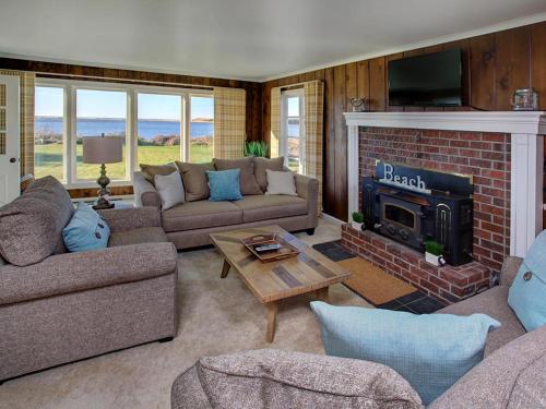 a living room with couches and a fireplace at Estuary Cottage in Seaside