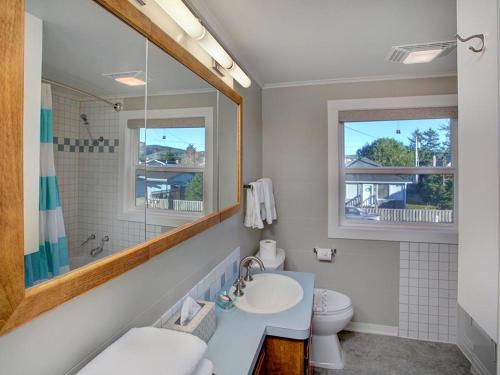 W łazience znajduje się umywalka, toaleta i lustro. w obiekcie Estuary Cottage w mieście Seaside