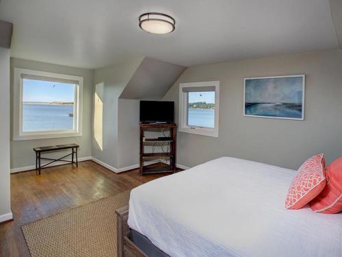 a bedroom with a bed and a tv and two windows at Estuary Cottage in Seaside