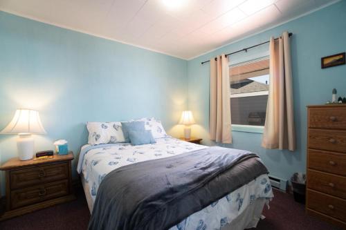 a blue bedroom with a bed and a window at Getaway Oceanfront Lodging in Rockaway Beach