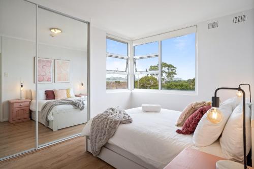 a white bedroom with a large window and a bed at Cute 2 Bedroom Apartment Kensington in Sydney
