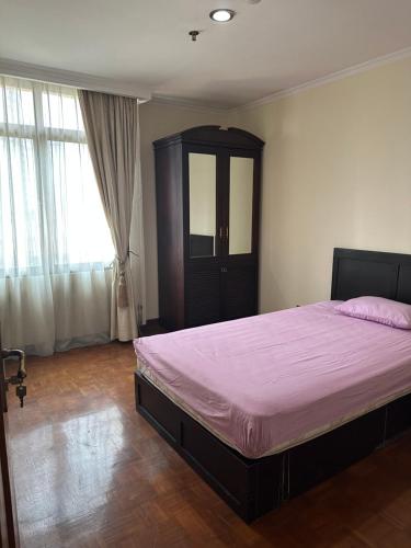 apartemen في جاكرتا: غرفة نوم بسرير كبير مع أرضية خشبية