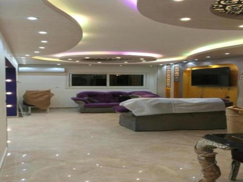 ein Wohnzimmer mit lilafarbenen Möbeln und einer Decke in der Unterkunft Alnahas St. Two-Bedroom Apartment With Jacuzzi in Tanta