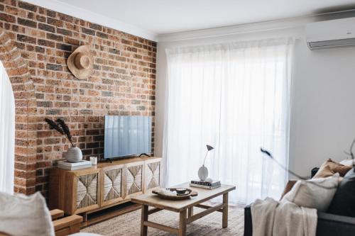 un salon avec un mur en briques et une télévision dans l'établissement Cavella North Beach, à Wollongong
