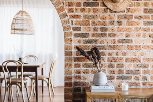 Cette chambre est dotée d'un mur en briques et d'une table avec un vase. dans l'établissement Cavella North Beach, à Wollongong