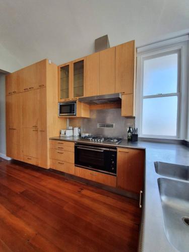 a kitchen with wooden cabinets and a large window at Tauranga - Big, beautiful Villa on the water! in Tauranga