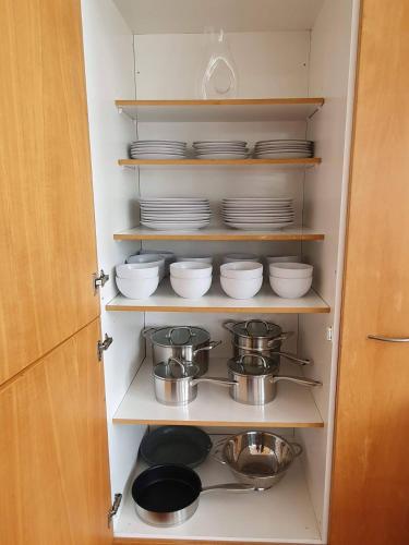 a cupboard filled with plates and bowls and pans at Tauranga - Big, beautiful Villa on the water! in Tauranga