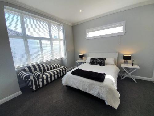 a bedroom with a bed and a chair and windows at Tauranga - Big, beautiful Villa on the water! in Tauranga