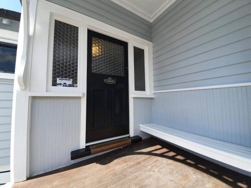 a porch with a black door and a bench at Tauranga - Big, beautiful Villa on the water! in Tauranga