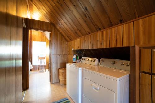 lavadora y secadora en una habitación con paredes de madera en The Cedar House en Otter Rock