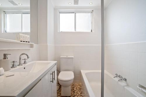 a white bathroom with a toilet and a sink at Cute 2 Bedroom Apartment Kensington in Sydney