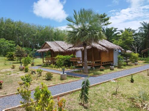 a small hut with a palm tree next to a road at Palm Garden Bungalow in Ko Lanta