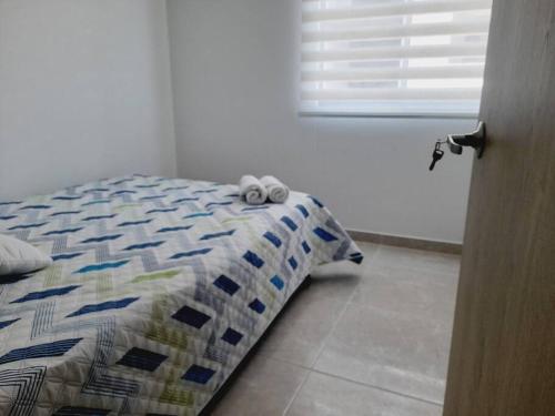 a bedroom with a bed with two towels on it at Hermoso apartamento con piscina ubicado cerca a los principales centros comerciales in Ibagué
