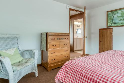a bedroom with a dresser and a bed and a chair at The Hamptons in Rockaway Beach