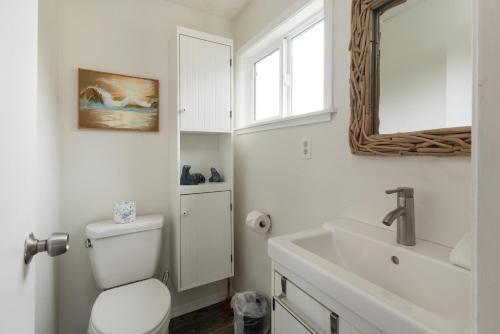 a bathroom with a toilet and a sink and a window at The Lakeside Caboose in Rockaway Beach