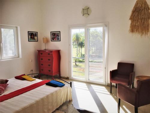 ein Schlafzimmer mit einem Bett, einem Stuhl und einem Fenster in der Unterkunft Residencia de Coco, Künstlerhaus in Piribebuy, in Piribebuy