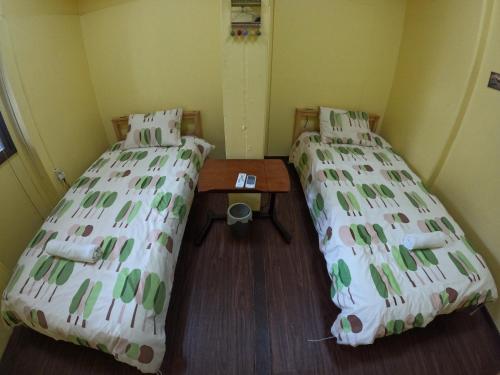 Zamamia International Guesthouse في Shimajiri: غرفة بسريرين وطاولة فيها