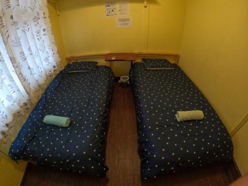 two beds in a small room next to a window at Zamamia International Guesthouse in Shimajiri