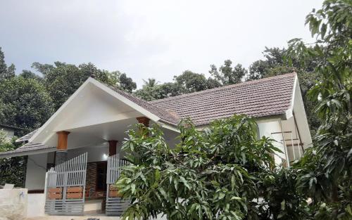 a white house with a gray roof at Green and Green in Vagamon