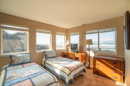 a bedroom with two beds and a desk and windows at Beach House in Lincoln City