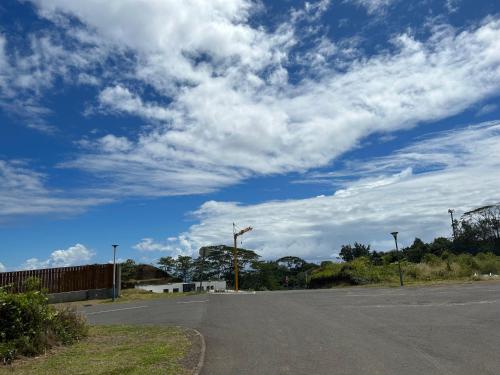 um parque de estacionamento vazio com um céu azul com nuvens em Cozy hills studio em Faaa