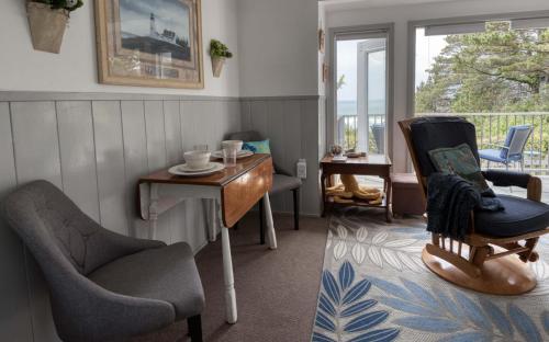 uma sala de estar com cadeiras, uma mesa e uma varanda em Breeze Cottage em Depoe Bay