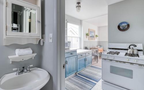 a white bathroom with a sink and a stove at Breeze Cottage in Depoe Bay