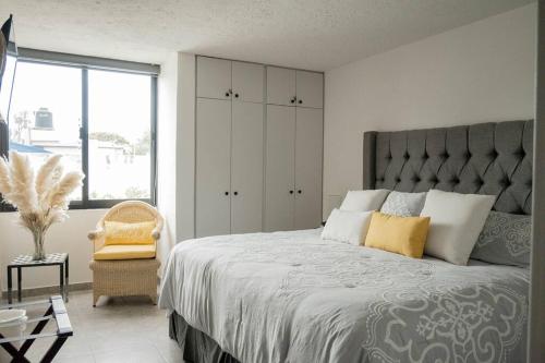 a bedroom with a large bed and a chair at NUEVO depto - Glorieta Chapalita in Guadalajara