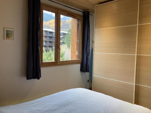 une chambre avec un lit et une fenêtre dans l'établissement Appartement 2 Pièces + Coin Montagne pour 6 avec Parking et Wi-Fi - FR-1-762-20, à Saint-Chaffrey