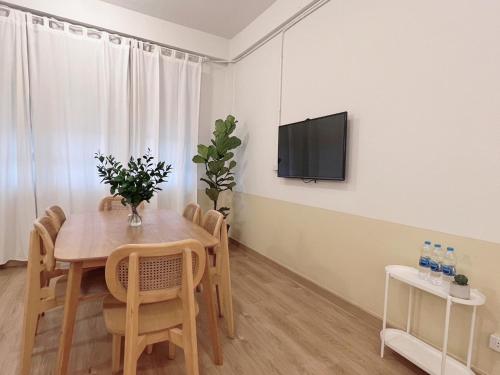 a dining room with a table and a tv on a wall at La Moon House in Salaya
