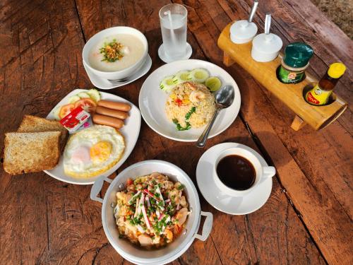 einen Tisch mit Tellern und einer Tasse Kaffee in der Unterkunft Sawasdee Lagoon Camping & Restaurant in Ban Lam Pi