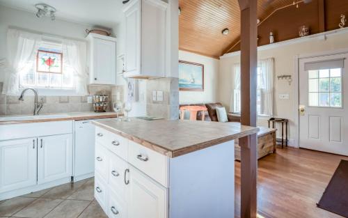 リンカーンシティにあるTaft Cottageの白いキャビネットと木製の天井が備わるキッチン