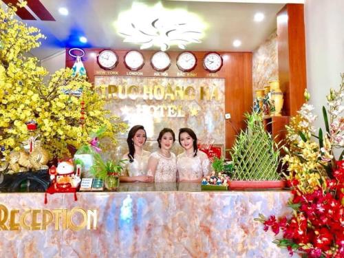 two women standing behind a counter with christmas trees at Trúc Hoàng Hà Hotel in Kon Tum