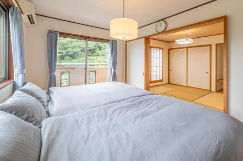 sypialnia z dużym łóżkiem i oknem w obiekcie ANGO ATAMI I w mieście Atami