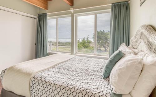 a bedroom with a bed and a large window at The Strand at Twin Rocks in Rockaway Beach
