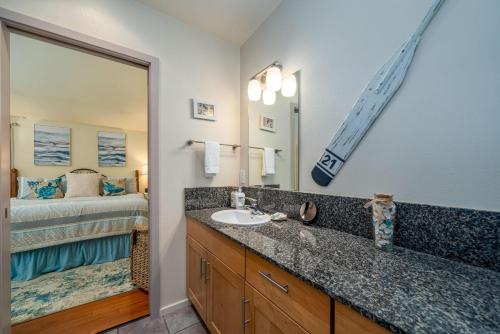 a bathroom with a sink and a mirror and a bed at Tranquility Cove in Depoe Bay
