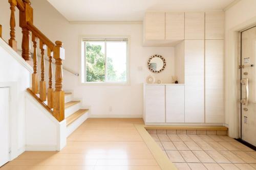 a staircase in a home with white walls and wood floors at ANGO KUJUKURI I in Yokoshibahikari