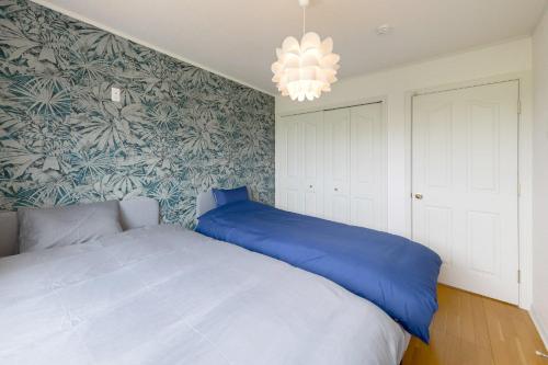 a bedroom with a large bed with a blue blanket at ANGO KUJUKURI I in Yokoshibahikari