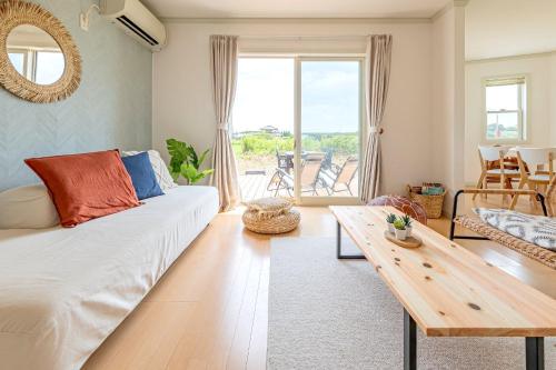 a living room with a white couch and a table at ANGO KUJUKURI I in Yokoshibahikari