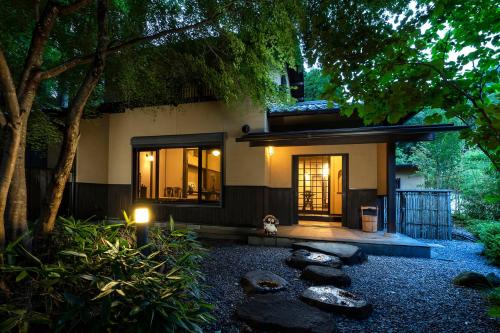 a house with a garden and some rocks and trees at Yufuin Yufusaryo in Yufuin