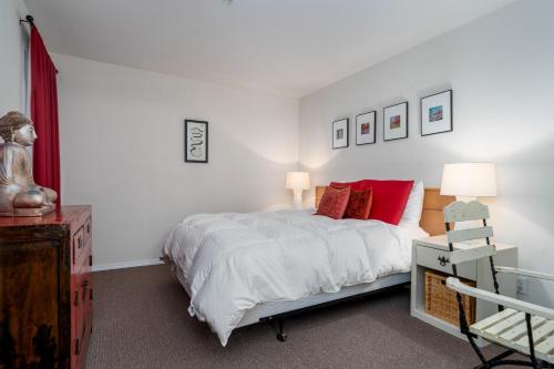 ein weißes Schlafzimmer mit einem Bett mit roten Kissen in der Unterkunft Waters Edge 410 in Lincoln City