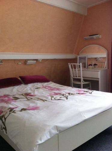a bedroom with a white bed with pink flowers on it at Hotel Brinkzicht in De Koog
