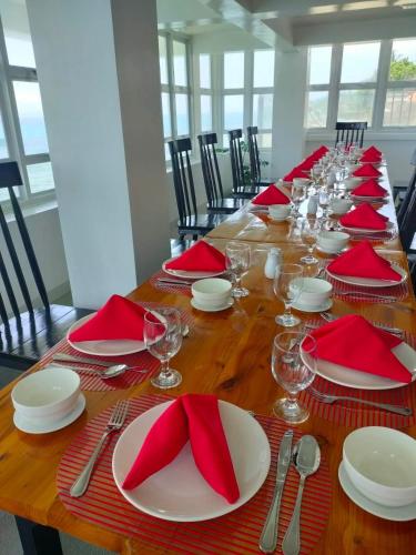 a long wooden table with red napkins and plates and glasses at The Marc Vannelli Oslob in Oslob