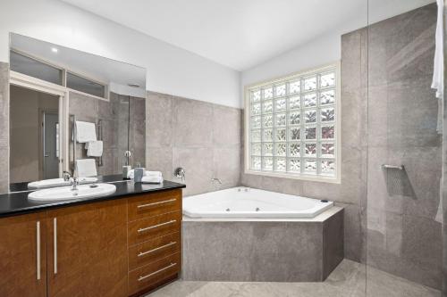 ein Bad mit einer Badewanne, einem Waschbecken und einem Fenster in der Unterkunft Rolig in Shoreham