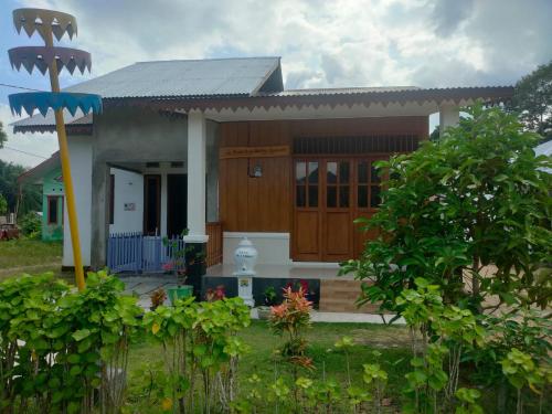 Homestay Melty Aprianti Tanjong Tinggi في Pasarbaru: منزل صغير وامامه حديقة